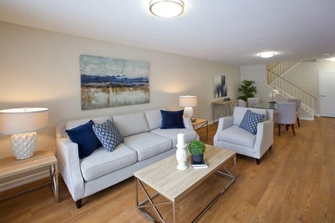A living room with a white couch, a coffee table, and a painting on the wall.
